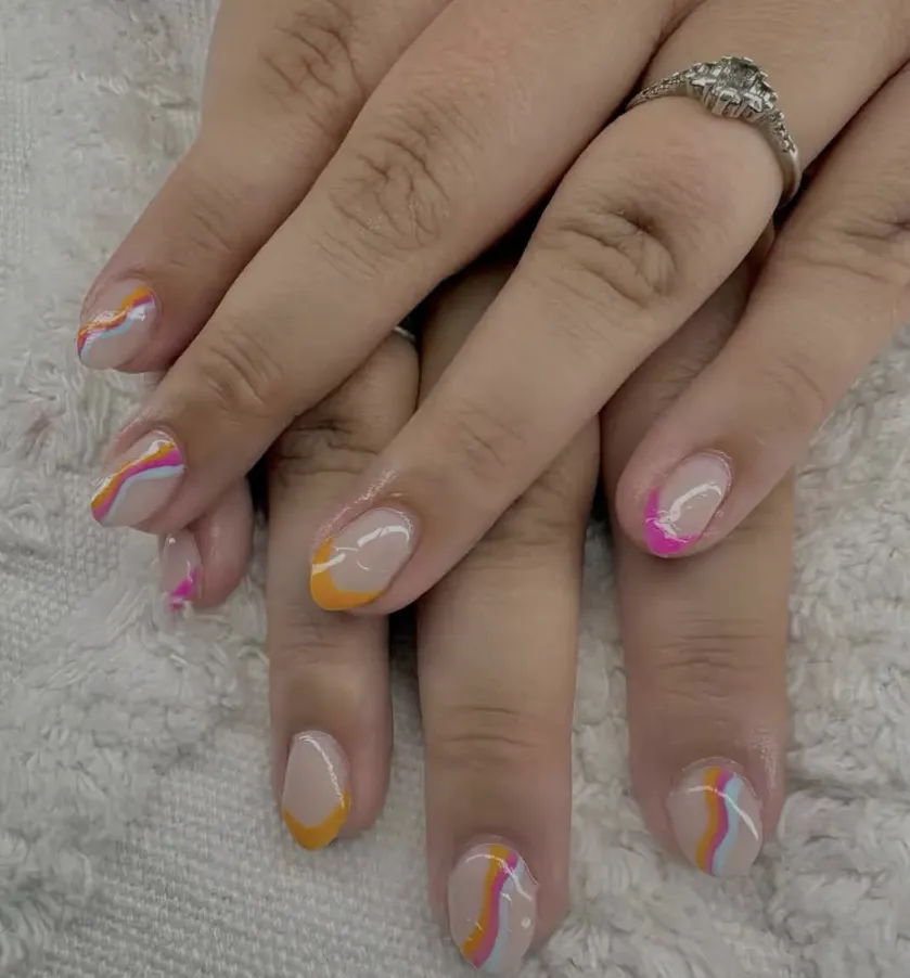 Nude nails with orange, pink and white swirls