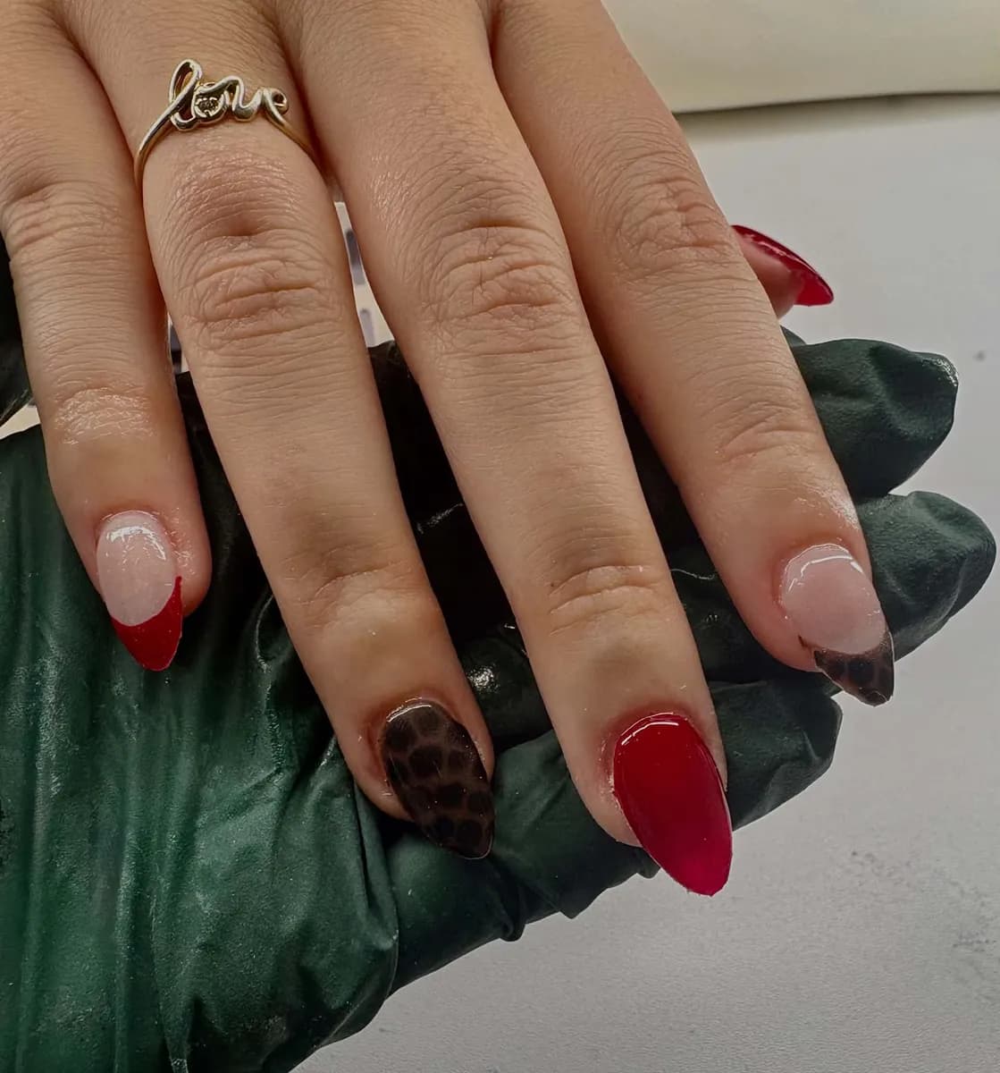 Red almond nails with a red French tip and a leopard print accent